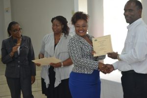 Permanent Secretary in the Ministry of Finance Colin Dore (right) presents a certificate of training to Vieda Mills at the closing ceremony of a Caribbean Development Bank funded training workshop at the St. Paul’s Anglican Church Hall on April 14, 2016. Facilitators Catherine Forbes (left) and Nicole Liburd are assisting with presenting certificates to participants